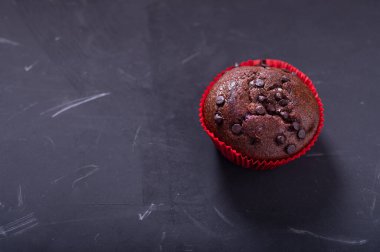 Koyu arkaplanda bir çikolatalı kek. Kırmızı pakette kek. Üst.