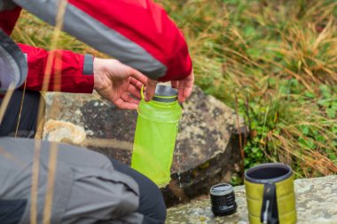 Nehirdeki su rezervlerinin yenilenmesi. Adam şişede su topluyor..