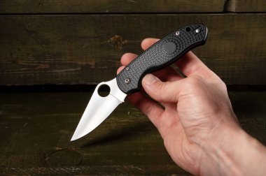 Bıçağı elinde tut. Bıçağı göster. Bıçakta bir delik var. Ahşap arkaplan.