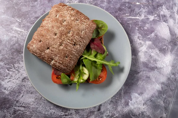 Uma sanduíche com um pão escuro e legumes. Hambúrguer com legumes. — Fotografia de Stock