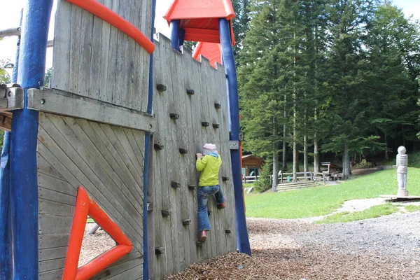 The child climbs the wall. Wall attraction for children. Child in clothes.