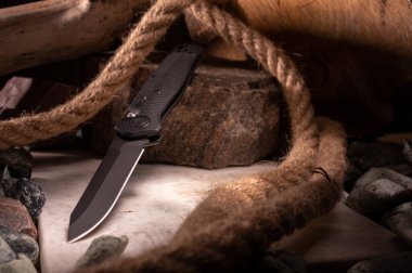 Bıçak, taşların ve iplerin arka planında bir açıda. Granit ve mermer taş üzerinde bıçak.