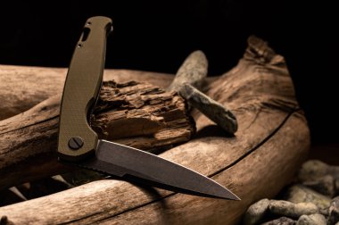 Bıçak katlanmış pozisyonda. Kavisli bıçak. Kütüğün üzerinde katlanan bıçak. Ön görünüm.