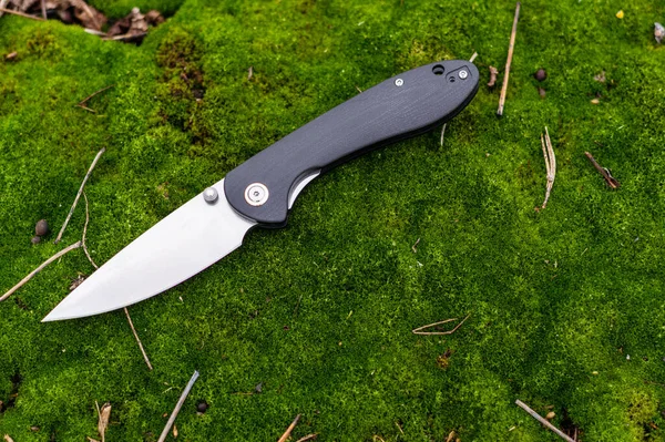 一把锋利的小刀躺在苔藓上 有黑色手柄的刀顶层 — 图库照片