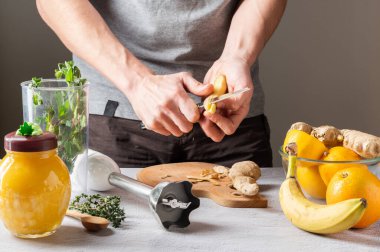 Kabuğundan zencefil kökü soy. Mutfakta temiz yemek var. Mutfak bıçağı elinde. Deriyi bıçakla yüzün..
