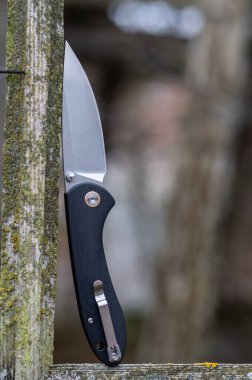 Siyah saplı ve şarjörü olan katlanmış bir bıçak. Sokaktaki bir bıçağın fotoğrafı. Dikey çerçeve.