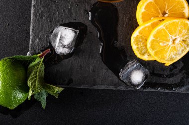 Doğal buz, limon ve nane. Siyah arka planda erimiş buz küpleri. Üst.