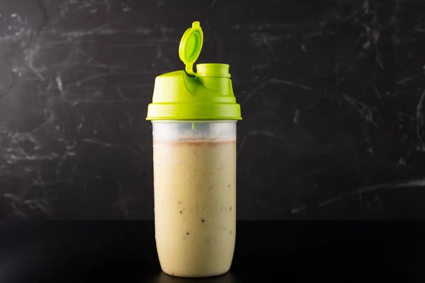 Shaker with fruit and protein drink. Shaker isolate on a dark background. Front view.