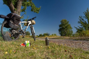 Tourist bike with a tent and a bag. Bicycle and sports nutrition. Cycling travel. Bicycle near the tree. clipart