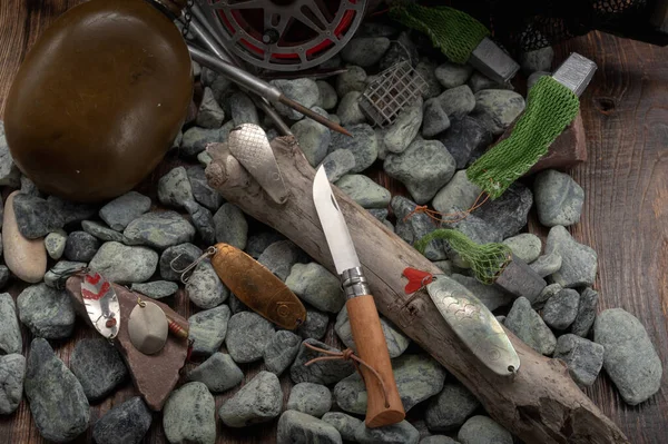 Fishing tackle and a knife on the stones. Pocket knife on wood. — Stockfoto