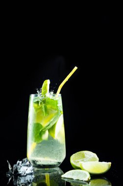 Siyah arka planda bir bardak mojito kokteyli. Limonlu ve naneli mojito. Dikey çerçeve.