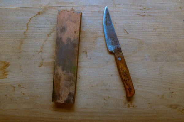 An old homemade knife and a whetstone. Sharpen a knife with a sharpening stone. Top.