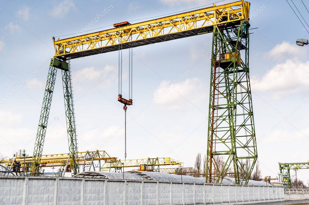 Large industrial crane. Crane for lifting large loads. The crane is behind the fence. Front view.