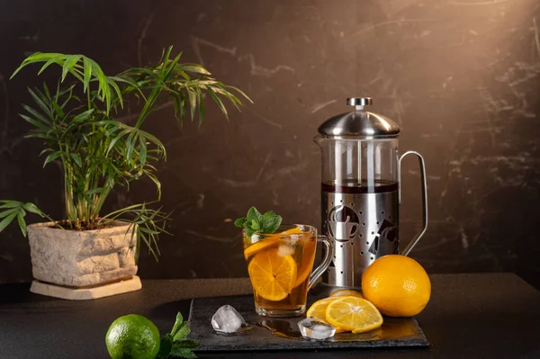 Tea with lemon and ice. Transparent mug with tea, ice and lemon. Mint and lemon.