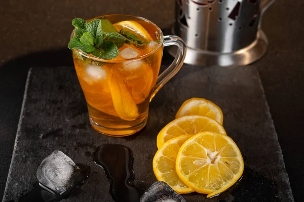 Iced tea with lemon and mint. Tea and ice cubes on a tray. Top view at an angle.