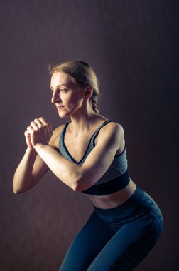 Kız çömeliyor. Fiziksel egzersizler. Spor aktiviteleri. Dikey çerçeve.