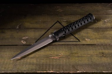 Uzun ve dar katlama bıçağı. Sapında delikler olan bir bıçak. Bıçağa bir açıdan bak..