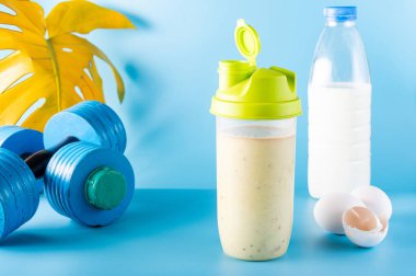 Süt ve yumurtalı protein karışımı. Kokteyl ve dambıl. Ön görünüm.