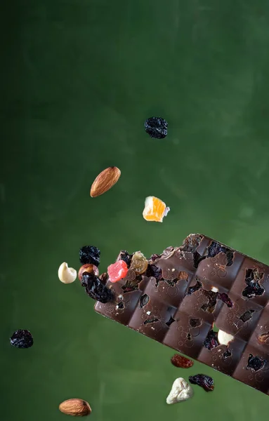 Létající ořechy a bobule. Mléčná čokoláda s ořechy. Čokoládová tyčinka s oříšky a bobulemi. Kousnutá čokoláda. — Stock fotografie