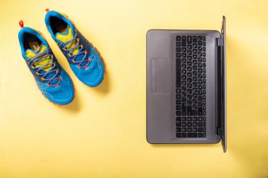 Koşu ayakkabıları ve laptop. İnternetten spor sayfasına giriyorum. Evde jimnastik ve fitness.