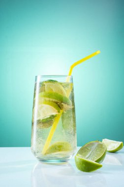 Bardakta limonata ve pipet pişiriyorum. Parlak ışık kompozisyonu. Limonata ve naneli.