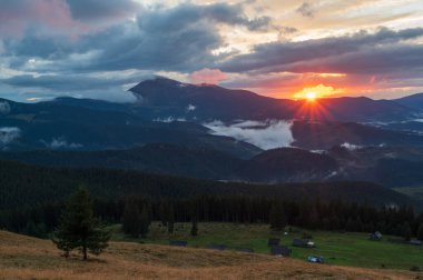 Güneş dağların arkasında batıyor. Dağların üzerinden güneş ışınları. Parlak güneş ışınları. Dağların üzerinden güneş. Manzara ve ufuk.