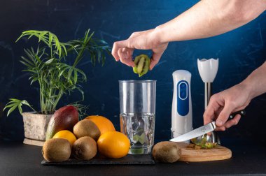 Meyve suyu için kivi dilimliyorum. Kivi dilimleri ve blender. Meyveleri karıştırıcıya at. Kivi dilimleri ve elinde bir bıçak..