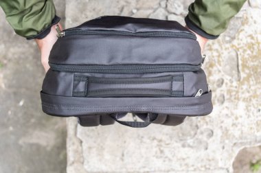 Orta ya da yakın çekim bir adamın sırt çantasını başka bir kişiye uzatma eylemini yakalar..