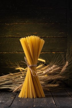 İtalyan mutfağına adanmış minimalist ve zarif bir hayat. Kompozisyon, dikey olarak yerleştirilmiş büyük, sıkıca sarılmış, çiğ ve kuru bir spagetti yığınının etrafında toplanıyor..