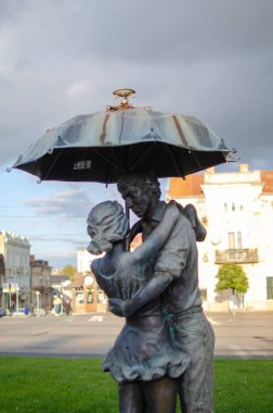 Bir çift heykel bir şemsiye altında kucaklaşır. Romantik, aşk, şehir meydanı. Seyahat için uygun.