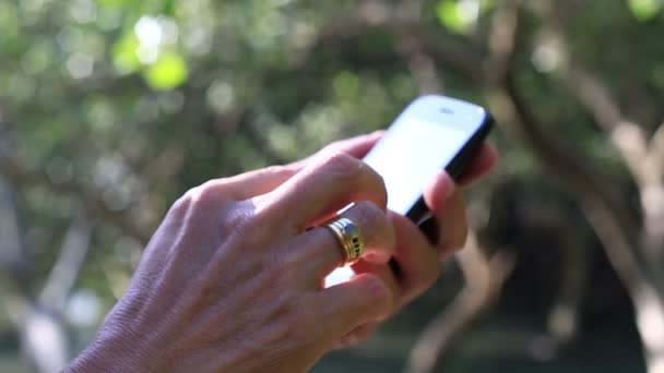 Primer plano de las manos del hombre usando Smartphone, Fondo de la naturaleza . — Vídeos de Stock