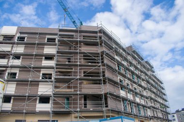 Arkaplanda binalar ve gökyüzü olan bir vinç ve arka planda binalar ve gökyüzü.