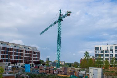 Arkaplanda binalar ve gökyüzü olan bir vinç ve arka planda binalar ve gökyüzü.