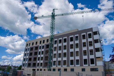 Yapı iskelesi, vinç ve mavi gökyüzü ve beyaz bulutlu bir bina.