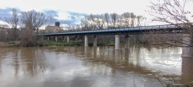 İspanya 'nın Logroo şehrinde kışın karanlık sularla kaplı uzun metal çerçeveli bir köprü.