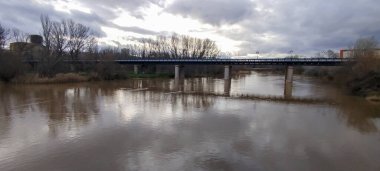 İspanya 'nın Logroo şehrinde kışın karanlık sularla kaplı uzun metal çerçeveli bir köprü.