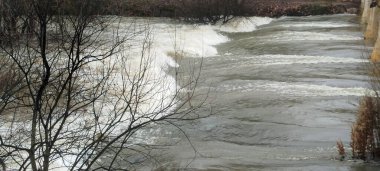 İspanya 'nın Burgos kentindeki hızlı akan bir nehirde, küçük bir barajın üzerinden akan dalgalı suyun yakın çekimi.