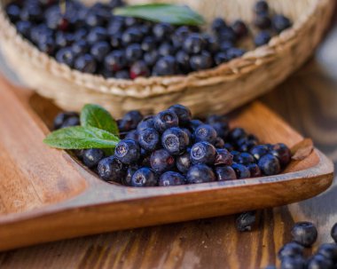 Taze yaprakları ile yaban mersini ahşap kase ve sepet makroda aldı. Islak ve parlak.