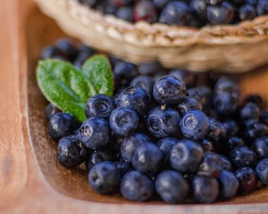 Taze çekilmiş yaban mersini makro fotoğraf kadar kapatın. Yeşil yaprakları ve ahşap plaka.