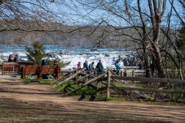 Great Falls National Park, VA, USA -- April, 3 2021. Photo of tourists observing the Great Falls from a viewing station in McLean, VA. clipart