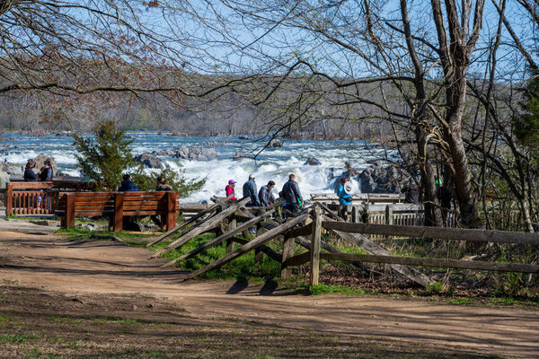 Great Falls National Park, VA, USA -- April, 3 2021. Photo of tourists observing the Great Falls from a viewing station in McLean, VA.