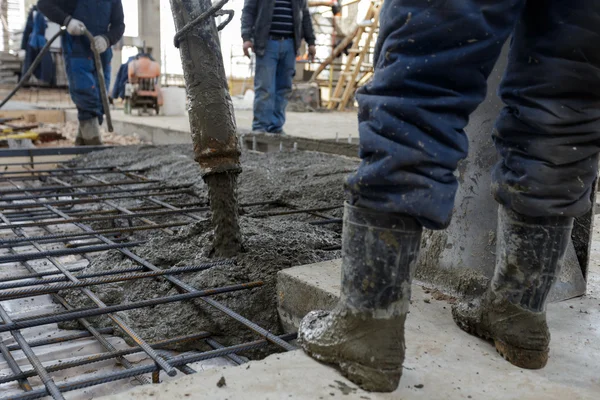 Construtores em botas de borracha metalurgia derramado concreto ou cimento — Fotografia de Stock