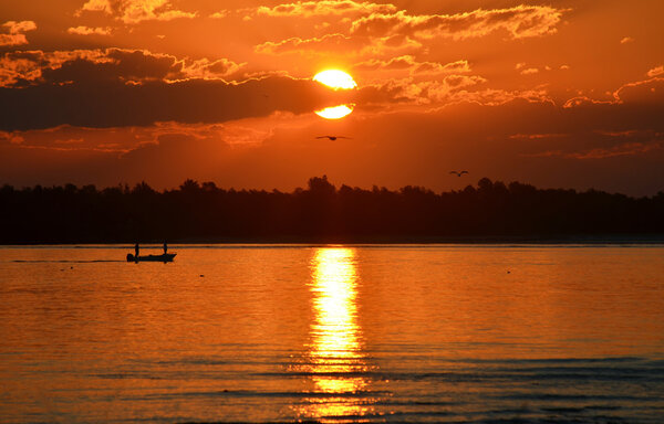 Силуэт рыболовного судна на воде на закате
