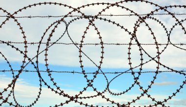 Gökyüzü arka plan ile karışık dikenli tel çit