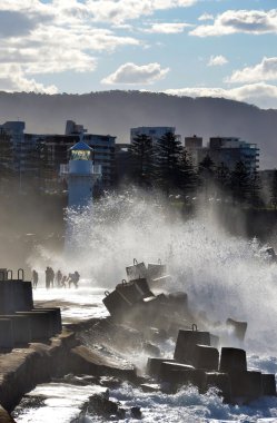Wollongong liman breakwall ve deniz feneri üzerinde büyük dalgalar çarptığında sıçrayan insanlar