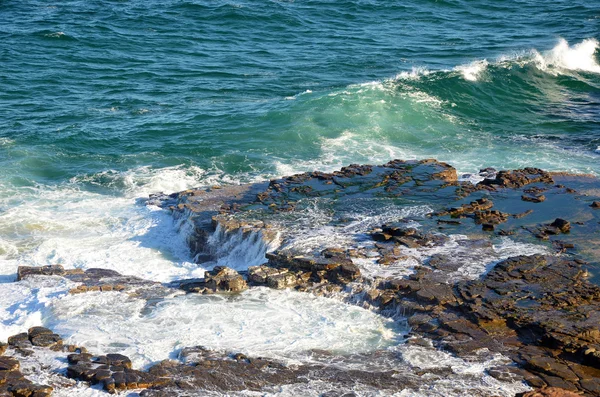 Wogende Wellen über einer tessellerten Felsplattform, die von Meereswellen verwittert ist — Stockfoto