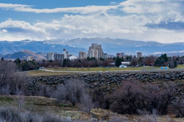 Reno Nevada - ABD - 26 Aralık 2025: Oteller ve Kumarhanelerle şehir merkezindeki Reno Cityscape gökdeleninin görüntüsü. Ön planda San Rafael Parkı ve arka planda karlı dağlar var. Gökyüzü bulutlu..