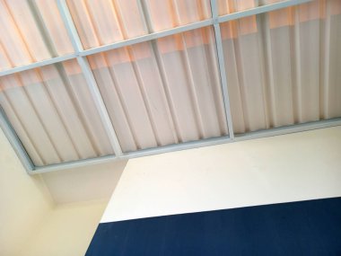 Mavi ve beyaz duvarlı, eğri büğrü metal bir çatının iç manzarası..