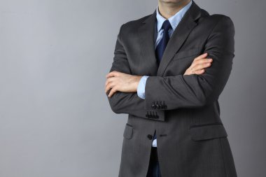 İş adamı gri arka plan üzerinde katlanmış elleriyle