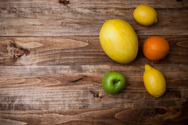 Orangen, Zitrone, Apfel und Melone auf Holz — Stockfoto